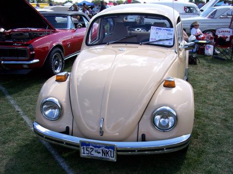 1972 Ford Ranchero - A tan Volkswagen Beetle is parked on grass at an outdoor car show, with other vehicles visible in the background.