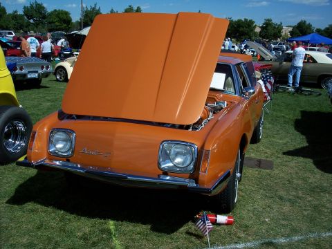 1972 Ford Ranchero - An orange AMC Pacer is displayed with its hood open at an outdoor car show.