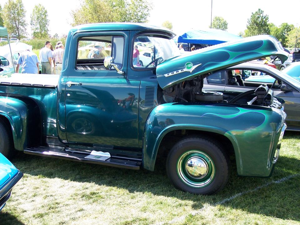 Green 1956 Ford F-100 pickup truck with flame decals and hood open
