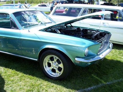 1972 Ford Ranchero - Teal 1967 Ford Mustang parked on grass with hood open, revealing the engine bay.