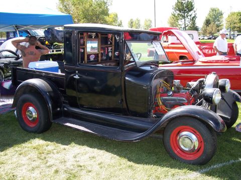 1972 Ford Ranchero - A black hot rod pickup truck with a custom interior and exposed engine is on display at an outdoor event.
