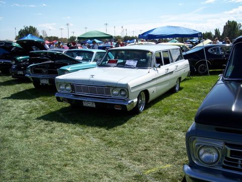 1972 Ford Ranchero - A white 1964 station wagon is displayed at an outdoor car show, with other vehicles and tents visible in the background.