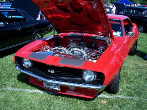 1972 Ford Ranchero - A red muscle car, possibly a 1969 Camaro SS, is displayed with its hood open at an outdoor car show.