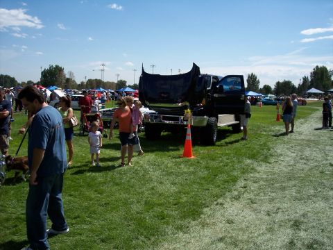 1972 Ford Ranchero - A large truck is displayed with its hood and door open at a sunny outdoor event with many other vehicles and people.