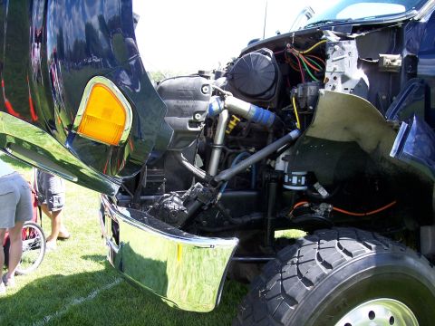 1972 Ford Ranchero - The engine compartment of a blue truck is visible with the hood raised, revealing the engine and various components.