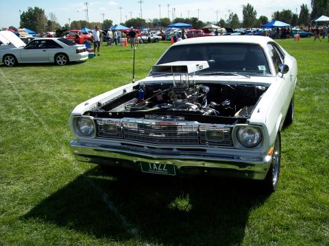 1972 Ford Ranchero - A modified Plymouth Duster is displayed at an outdoor car show with its engine exposed.