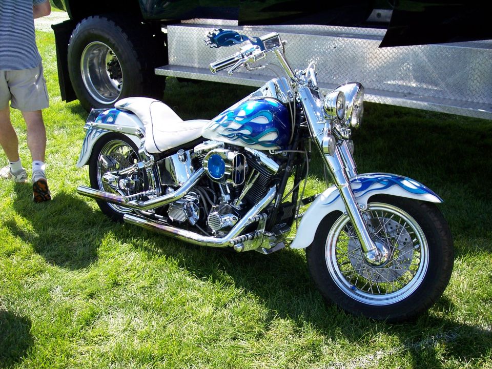 White motorcycle with blue flame graphics and chrome accents parked on grass