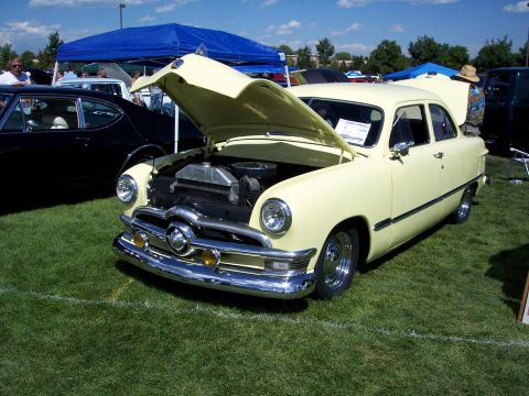 1972 Ford Ranchero - A pale yellow 1950 Ford Custom sedan is displayed with its hood open at an outdoor car show.