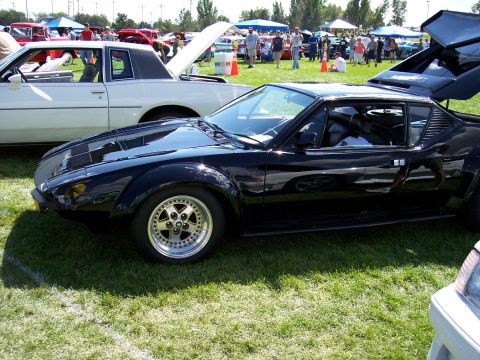 1972 Ford Ranchero - A black sports car with distinctive gullwing doors and aftermarket wheels is displayed on a grassy field at an outdoor car show.