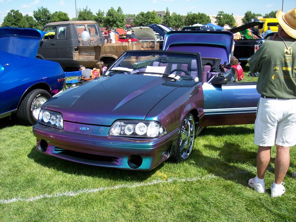 Fox-body Mustang convertible in purple-teal chameleon paint at a grass car show