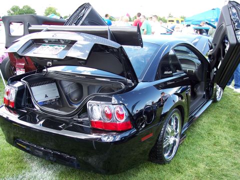 1972 Ford Ranchero - Customized black coupe with gullwing doors and a large rear spoiler is displayed on grass.