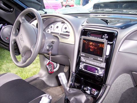 1972 Ford Ranchero - The interior of a car features a custom dashboard with a large screen and audio system, along with a Mustang emblem on the steering wheel.