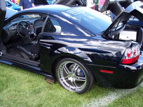1972 Ford Ranchero - A black Ford Mustang is displayed on a grassy field, its custom features and audio system.