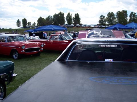 1972 Ford Ranchero - A black Ford Ranchero is seen from the rear at an outdoor car show, with other vehicles and tents in the background.