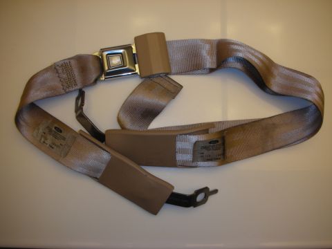 1998 Ford Crown Victoria - tan automotive seat belt with a chrome push-button buckle and Ford-labeled webbing coiled on a tan surface.