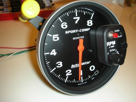1998 Ford Crown Victoria - angled view of an Auto Meter Sport-Comp Monster tachometer with its wiring harness and a yellow shift light.