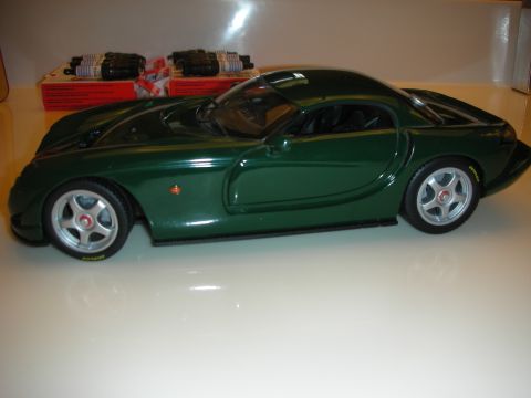 1998 Ford Crown Victoria - British racing green diecast sports coupe model shown in full side profile with silver wheels on a tan surface.