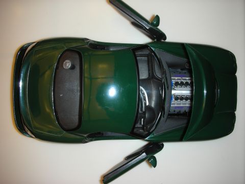 1998 Ford Crown Victoria - Overhead view of a dark green die-cast model sports car with its doors and hood detached, exposing the engine bay.