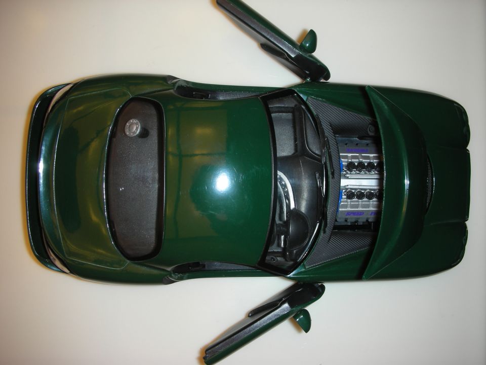 Top-down view of dark green die-cast model sports car with doors and hood removed showing engine