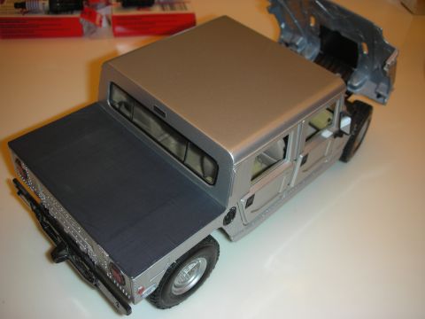 1998 Ford Crown Victoria - Rear-quarter view of a tan die-cast model of a boxy 4x4 crew-cab utility truck with a hard top and open pickup bed.