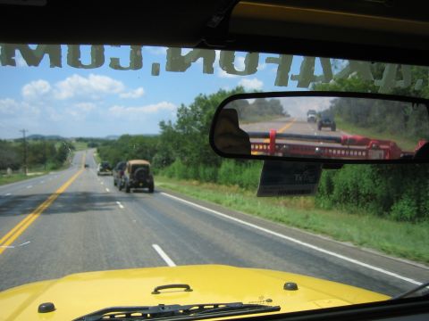 2001 Jeep Wrangler - View from inside a yellow Jeep on a highway, with several other Jeeps in the distance and a TX Tag on the rearview mirror.