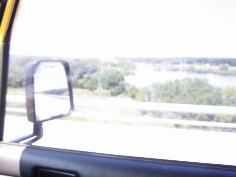 2001 Jeep Wrangler - View from inside a vehicle shows a side mirror reflecting the road ahead and a scenic landscape.