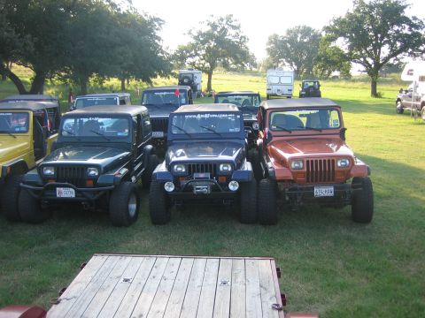 2001 Jeep Wrangler - A group of Jeep Wranglers are parked together on a grassy area, with trees and campers visible in the distance.