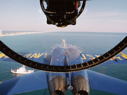 1999 Lincoln Town Car - A Blue Angels jet flies over the ocean, with a boat visible below and a city skyline in the distance.