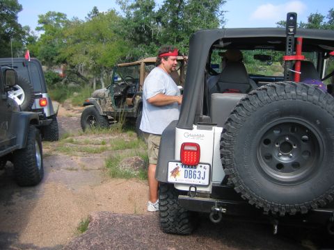 2001 Jeep Wrangler - Several Jeeps are parked on a rocky, off-road trail with trees in the background.