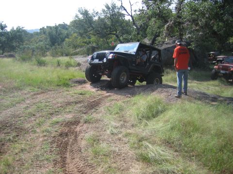 2001 Jeep Wrangler - A black 2001 Jeep Wrangler navigates an off-road trail with other vehicles visible in the background.