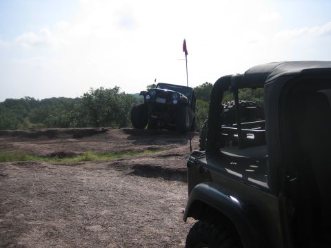 2001 Jeep Wrangler - Two Jeep Wranglers navigate a rocky, off-road terrain under a partly cloudy sky.