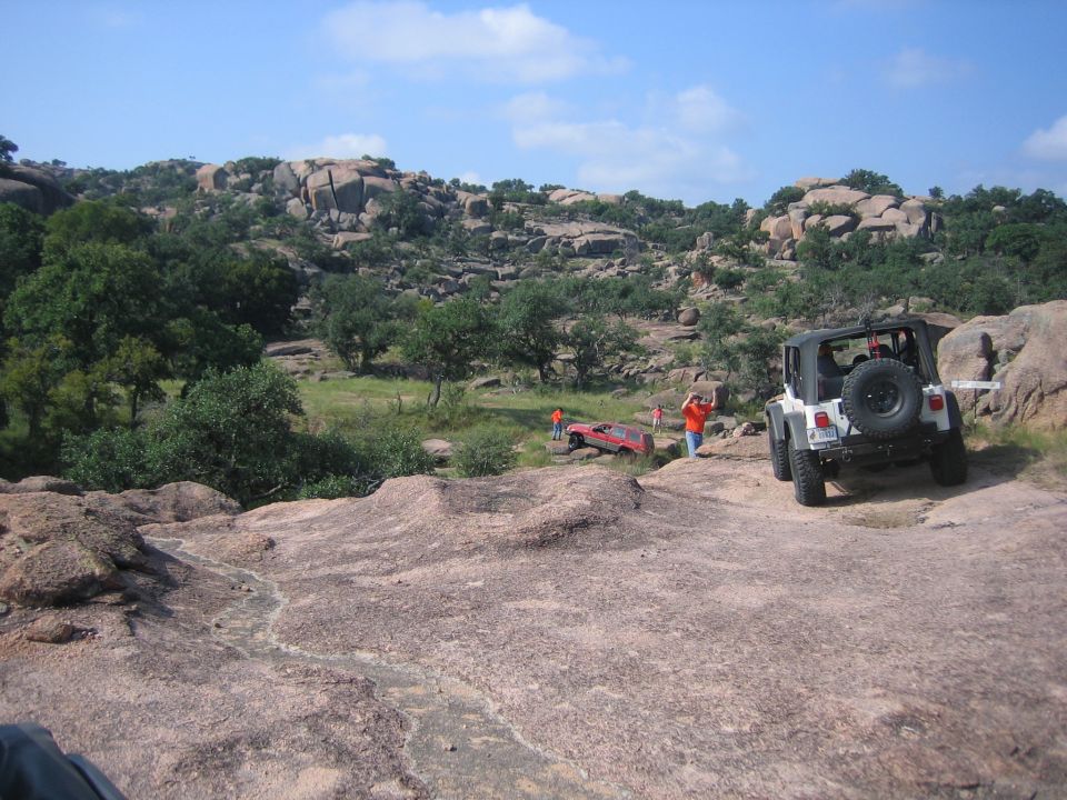 White 2001 Jeep Wrangler viewed from rear on rocky trail with red Jeep in background
