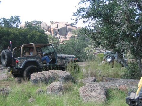 2001 Jeep Wrangler - A camouflaged Jeep Wrangler navigates a rocky, off-road trail with another Jeep visible in the background.
