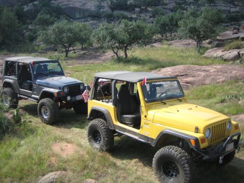 2001 Jeep Wrangler - Two Jeep Wranglers are parked on a rocky, grassy hillside under a clear sky.