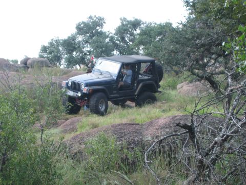 2001 Jeep Wrangler - A blue 2001 Jeep Wrangler navigates a rocky, off-road trail under an overcast sky.