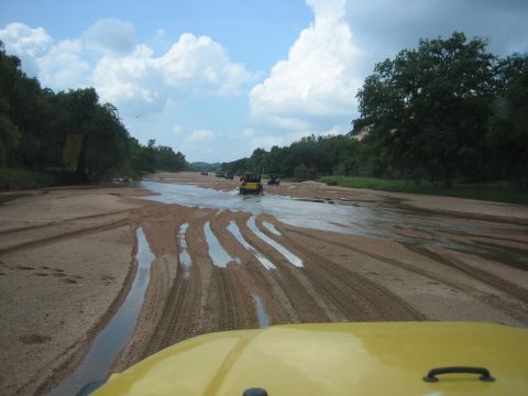 2001 Jeep Wrangler - A convoy of Jeep Wranglers navigates a sandy riverbed under a cloudy sky.