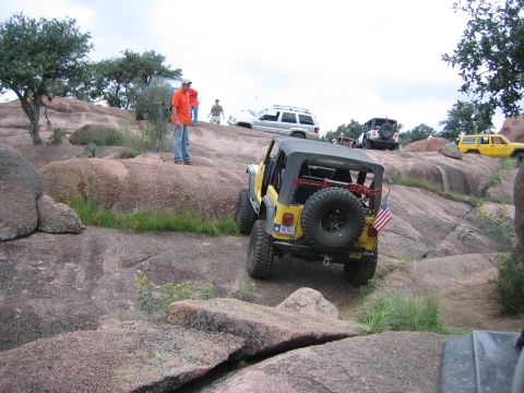 2001 Jeep Wrangler - Multiple Jeeps and SUVs navigate a rocky off-road trail under a cloudy sky.
