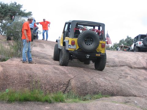 2001 Jeep Wrangler - A yellow Jeep Wrangler navigates a rocky trail with other vehicles and people present.