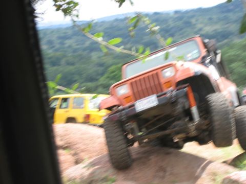 2001 Jeep Wrangler - Two Jeeps off-roading on a rocky trail with trees and hills in the distance.