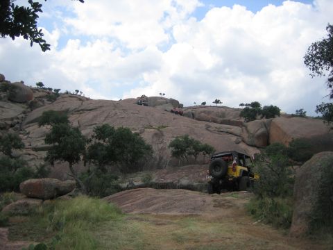2001 Jeep Wrangler - Off-road vehicles navigate a challenging, rocky landscape with scattered trees and boulders.