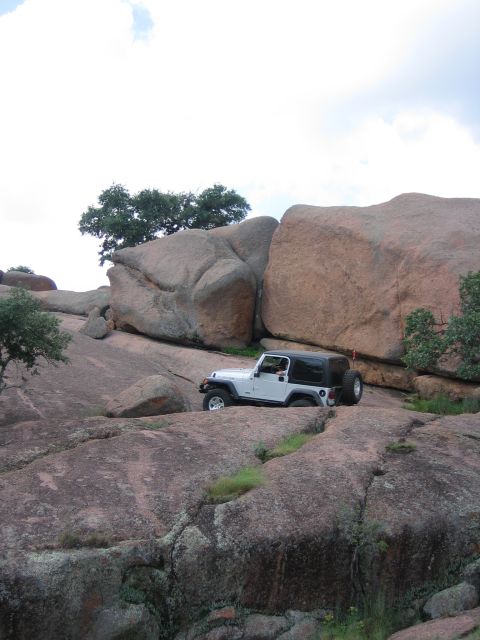 2001 Jeep Wrangler - A white Jeep Wrangler navigates a rocky landscape under a cloudy sky.