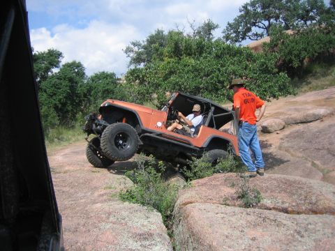 2001 Jeep Wrangler - A 2001 Jeep Wrangler tackles a challenging rocky obstacle with a trail guide observing.