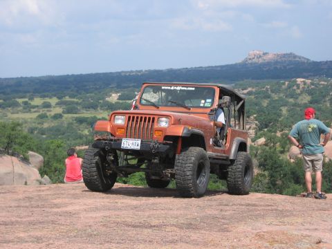 2001 Jeep Wrangler - A modified Jeep Wrangler sits on a rocky outcrop overlooking a valley, with two onlookers observing the landscape.