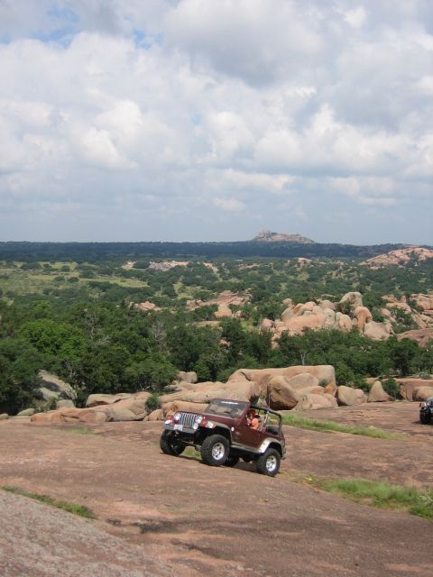 2001 Jeep Wrangler - A maroon 2001 Jeep Wrangler navigates a rocky, off-road landscape.