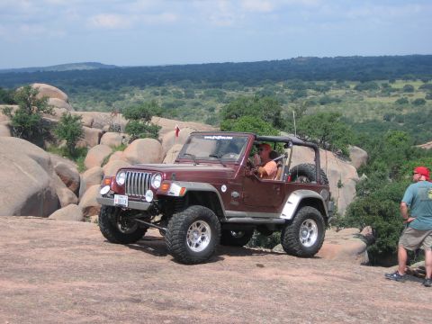 2001 Jeep Wrangler - A Jeep Wrangler navigates a rocky landscape under a partly cloudy sky.