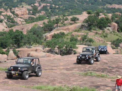 2001 Jeep Wrangler - Several Jeep Wranglers navigate a rocky, outdoor landscape with scattered trees and large boulders.