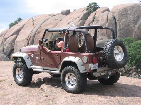 2001 Jeep Wrangler - A red 2001 Jeep Wrangler is parked on a rocky surface with large boulders in the background.