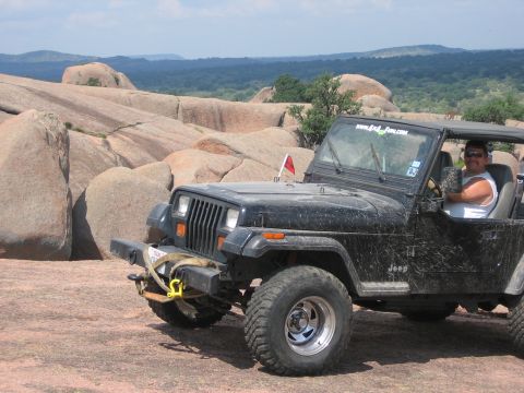 2001 Jeep Wrangler - Man driving a black Jeep Wrangler in a rocky, scenic landscape.