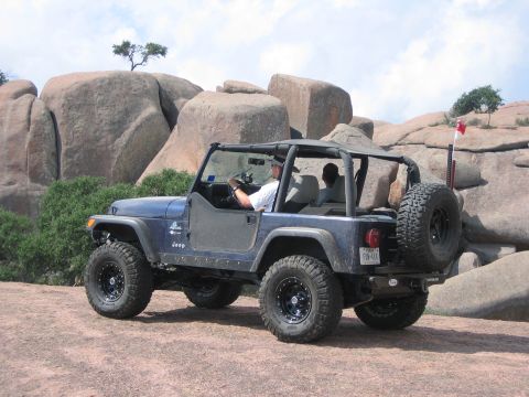 2001 Jeep Wrangler - 2001 Jeep Wrangler navigating a rocky trail with large boulders in the background.