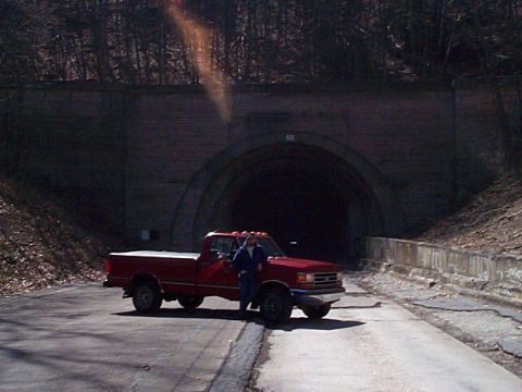 1989 Ford F-150 - A red pickup truck is parked on a road in front of a large tunnel entrance.